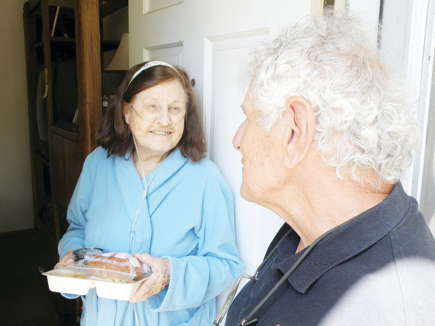 In a photo from 2018, Joanne Lopez, left, gets lunch from Nourish Meals on Wheels delivery driver Geno Pauline. Lopez, 82, can no longer drive, and her daughter Tria lives in the mountains, so the meals and companionship Pauline brings are vital.